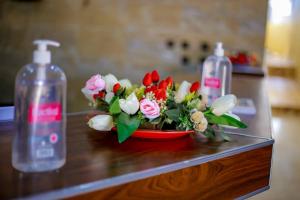 a bouquet of flowers in a bowl on a counter with two bottles at Hotel Etoile De Kennedy in Bouaké