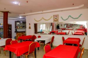 a restaurant with red tables and chairs and a mirror at Hotel Etoile De Kennedy in Bouaké