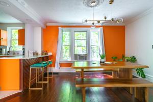 a kitchen with orange walls and a wooden table at Prime Location Top Rated Clean Parking Free! in Columbus