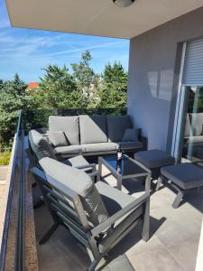 a patio with a couch and chairs on a balcony at Apartment Mare D with a pool new in Novalja