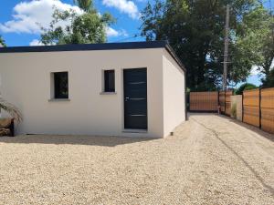 a white garage with a black door on a gravel driveway at LEntre-Deux Week-ends in Cléguer