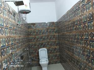 a bathroom with a toilet and a wall of tiles at Panchkedar resort in Sonprayag