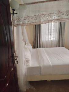 MbitaにあるLakeview Apartments - Cozy Greyのベッドルーム(天蓋付き白いベッド1台付)