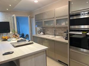 eine Küche mit Küchengeräten aus Edelstahl und einer Arbeitsplatte in der Unterkunft Maison Chic à 10min du circuit des 24H in Allonnes