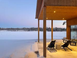 a porch with two chairs and a table on a frozen lake at Lapland Riverside Escape in Rovaniemi