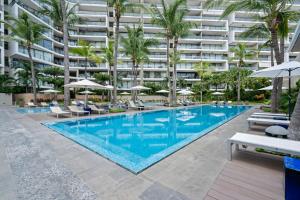 a swimming pool with chairs and umbrellas in front of a building at Nima Bay Oasis, Ground Floor with Private Garden in Puerto Vallarta