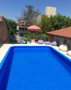 a blue swimming pool with chairs and an umbrella at Hotel posada sol in Villa Carlos Paz