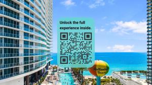 a sign in front of a building next to the ocean at Gorgeous Views Await in Your Beachfront Condo in Hollywood