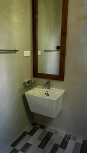 ein Badezimmer mit einem weißen Waschbecken und einem Spiegel in der Unterkunft Вилла с бассейном и видом на рисовые поля и джунгли in Weligama