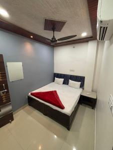 a bedroom with a bed with a red blanket on it at Annapurna Hotel in Ujjain