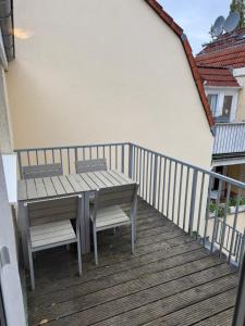 a wooden deck with a table and chairs on a balcony at H&H Apartments im Herzen der Stadt in der Lange Strasse geräumig ruhig mit Küche und Esstisch in Greifswald