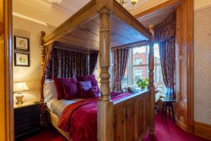 a bedroom with a canopy bed with purple pillows at Brooklands 5 Star Guest House in Penrith