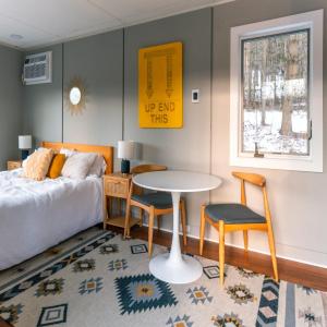 Un dormitorio con una cama y una mesa y sillas. en Modern Tiny House with hot tub & river near Stowe, en Johnson