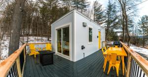 Una pequeña casa con sillas amarillas en una terraza. en Modern Tiny House with hot tub & river near Stowe, en Johnson