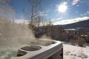 a hot tub covered in snow with the sun in the background at Lemond Place Home in Snowmass Village