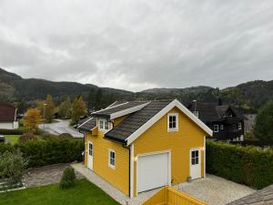 沃斯Sandvik Garasjeloft的一座黄色房子,上面有太阳能电池板