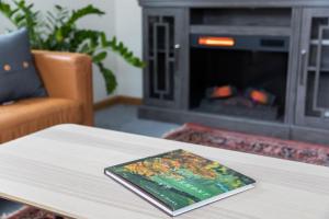 un libro appoggiato su un tavolino da caffè con un camino di Smuggler's Notch Mountain House with hot tub & river a Morses Mill