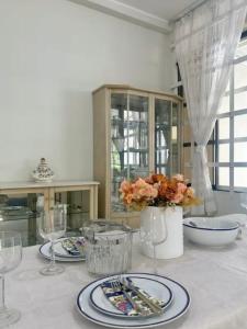 a white table with plates and glasses and flowers on it at Duplex de 2 habitaciones y 3 baños in Jaén