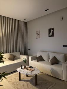 a living room with two white couches and a table at شقة مطلة على البرج - غرفه وصالة in Al Kharj