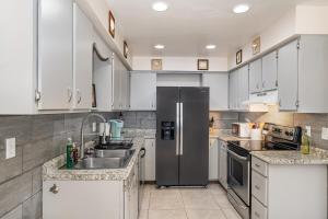 una cucina con frigorifero in acciaio inossidabile e mobili bianchi di Beachy Retreat - Atlas Duplex a Satellite Beach Altre 18 foto