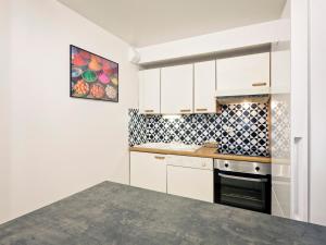 a kitchen with white cabinets and a black oven at Duplex spacieux 8 pers avec parking, balcon et Wifi - Centre de Brides-les-Bains - FR-1-512-177 in Brides-les-Bains