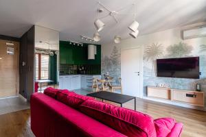 a living room with a red couch and a kitchen at Grand Apartments - Apartments SPA Waterlane Island in Gdańsk
