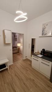 a kitchen with white cabinets and a living room at Deichliebe 3 - gemütlich, zentral und modern- Inklusive privater Stellplatz im Parkhaus 2min zu Fuß entfernt in Bremerhaven