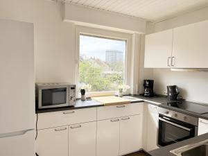a white kitchen with a microwave and a window at City Rooms Heppenheim in Heppenheim an der Bergstrasse +22 photos