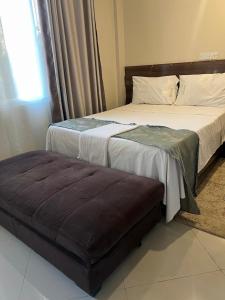 a bedroom with two beds and a ottoman in it at holm's home studio in Diani Beach