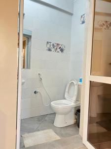 a white bathroom with a toilet and a shower at holm's home studio in Diani Beach