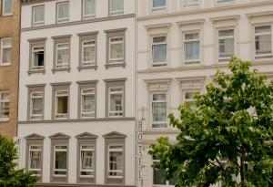 ein weißes Gebäude mit Fenstern und einem Baum in der Unterkunft Hotel Residence am Hauptbahnhof in Hamburg