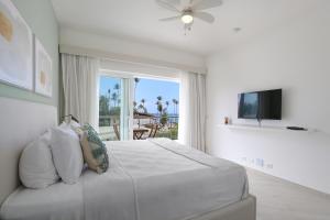 a white bedroom with a large bed and a window at Destination Jelly / Playa Coral Condo in Punta Cana