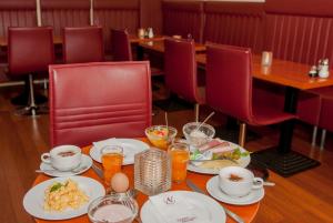 ハンブルクにあるホテル レジデンス アム ハウプトバーンホフの食器と赤い椅子が並ぶテーブル