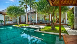 uma piscina numa villa com palmeiras em Villa Odyssey em Seminyak