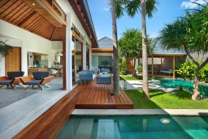 um deque exterior com uma piscina e palmeiras em Villa Odyssey em Seminyak