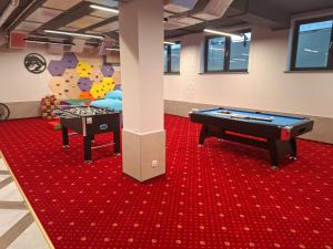 two pool tables in a room with red carpet at Apartamenty Grapa Resort 2xSauny 2xSale zabaw Balia Kulkolandia in Białka Tatrzańska