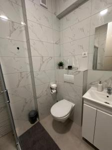 Un baño blanco con inodoro y lavabo. en Spa Apartman Love&Spa, en Banja Luka