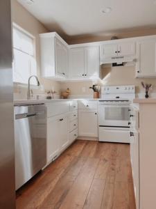 Una cocina blanca con electrodomésticos blancos y suelos de madera. en Centrically Located Hillsboro Home, en Hillsboro