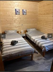 two beds in a room with wooden walls at Chata Sovička in Kokava na Rimavica