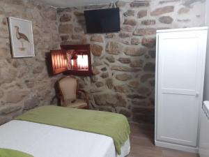 a bedroom with a bed and a tv on a stone wall at Casa do Galego  +42 photos