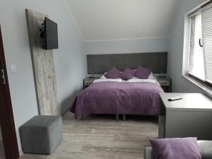 a bedroom with a bed with purple sheets and purple pillows at Villa Kris in Pobierowo