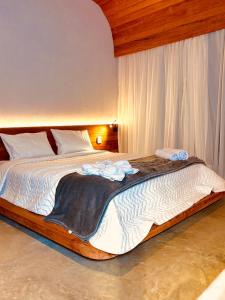 a bedroom with a large bed with white sheets at Flor do Umarí Eco Hotel e Eventos in Serra de São Bento