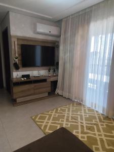 sala de estar con TV y ventana grande en Refúgio pôr do sol Fe, en Marechal Cândido Rondon