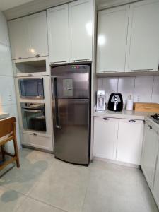 una cocina con nevera de acero inoxidable y armarios blancos en Refúgio pôr do sol Fe, en Marechal Cândido Rondon