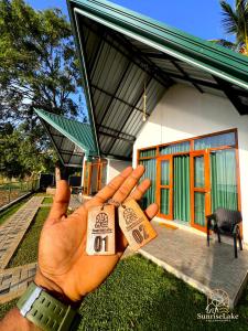 a hand holding two pieces of paper in front of a house at Sunrise Lake Resort in Polonnaruwa