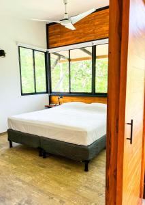 a bedroom with a large bed in a room with windows at Oleadas Maderas in San Juan del Sur