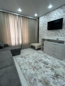 uma sala de estar com um sofá e uma televisão na parede em Beautiful DAY em Almaty