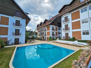 a swimming pool in front of two buildings at Capivari Flat in Campos do Jordão