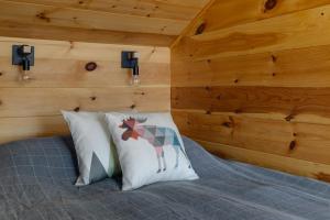 a bedroom with wooden walls and a bed with two pillows at Cabin N1 Les Grand'Pares Lake view Jacuzzi in Saint-Aimé-Du-Lac-des-Îles