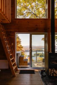a view from the living room of a cabin with a large window at Cabin N1 Les Grand'Pares Lake view Jacuzzi in Saint-Aimé-Du-Lac-des-Îles +13 photos